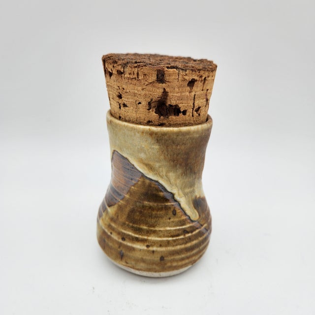 Tall waisted stoneware jar with layered brown and cream drip glaze, fitted natural cork stopper, signed "LAIR" on base