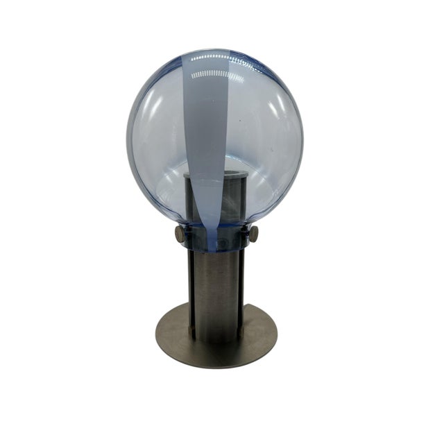 They feature cylindrical metal bases with circular platforms and spherical shades of blown glass, made using the membrane...