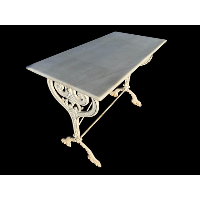 A bistro table from the 1900s, originally from a Parisian brasserie, with floral cast iron and wrought iron legs and a...