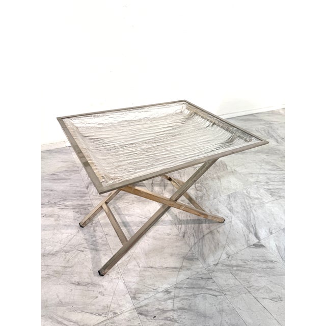 Unique mid-century folding tray table featuring a striking textured Lucite top with an ice-like finish, framed in sleek...