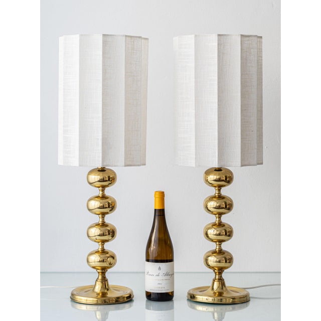 A sculptural pair of Swedish mid-century modern brass table lamps by Aneta, featuring stacked globe (bobbin) stems and new...
