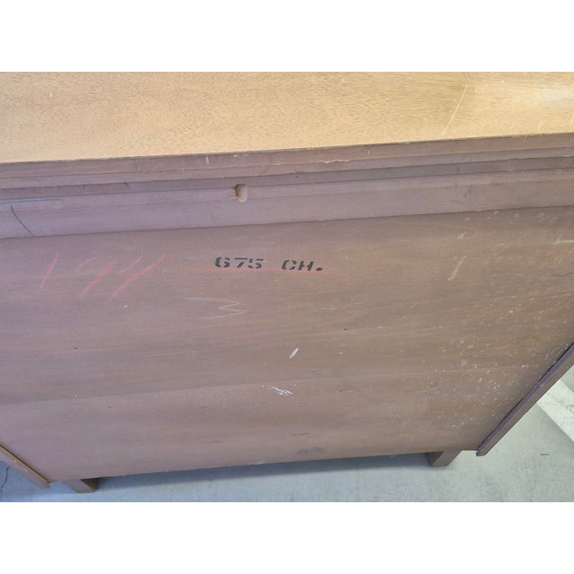 This is a Mid-Century Modern tallboy chest of drawers crafted from light-toned wood with a prominent natural grain. It...