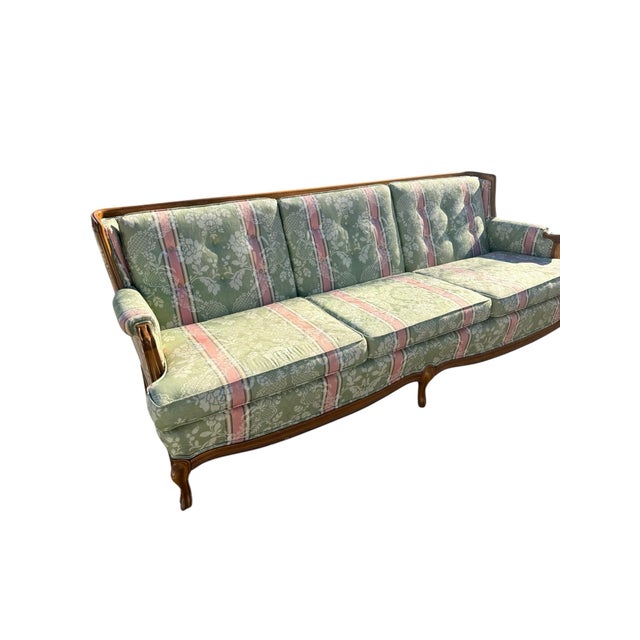 This pink and green upholstered sofa, with its carved wooden frame, cabriole legs, and fioral upholstery, clearly draws...