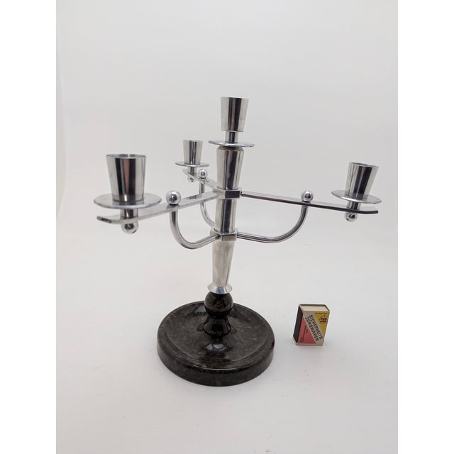 A striking Art Deco candlestick in the WMF style, made of polished aluminum, with a bowl-shaped, brown marble base or...