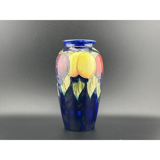 This exquisite 1920's Moorcroft miniature vase features the classic Wysteria and plum decoration, beautifully contrasted...