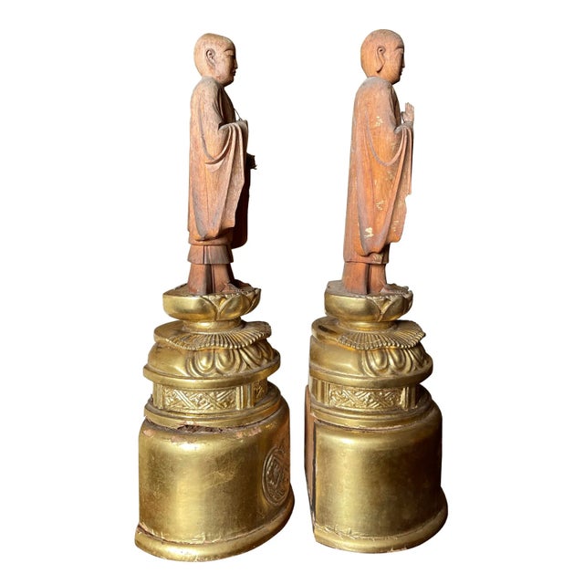 A pair of carved monks from the Taishō period. With meditative gestures, one holding a strand of prayer beads. On carved...