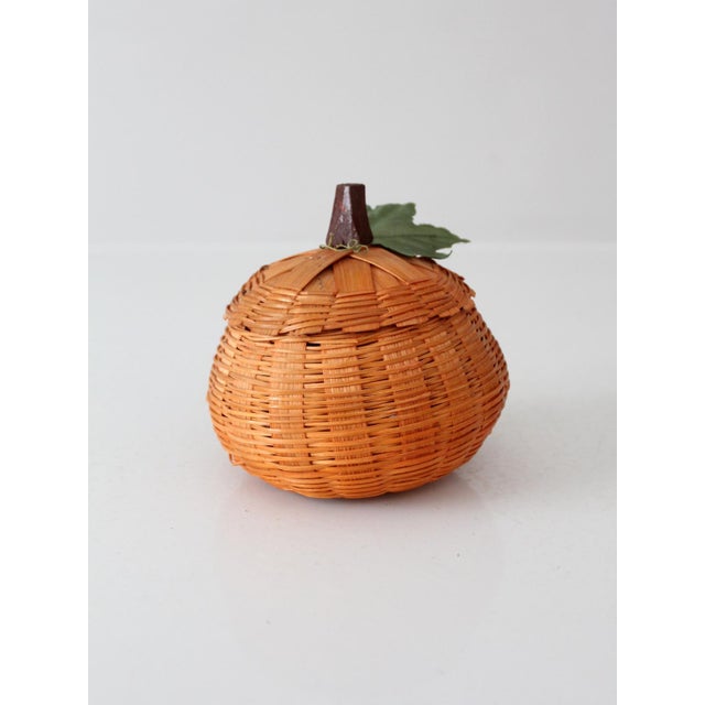 Vintage pumpkin basket in a warm orange finish, with a rounded silhouette, leafy top, and removable lid. A charming accent...