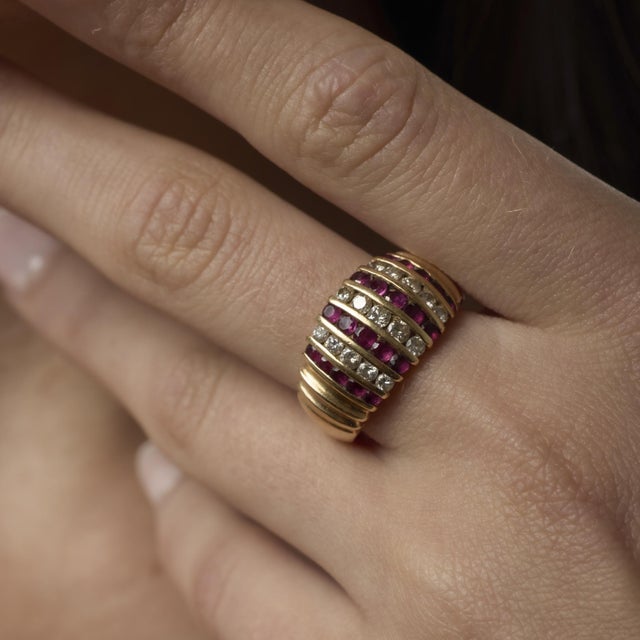 A vibrant vintage 14k yellow gold ring adorned with 0.70 carats of vivid rubies and 0.50 carats of sparkling H color SI...