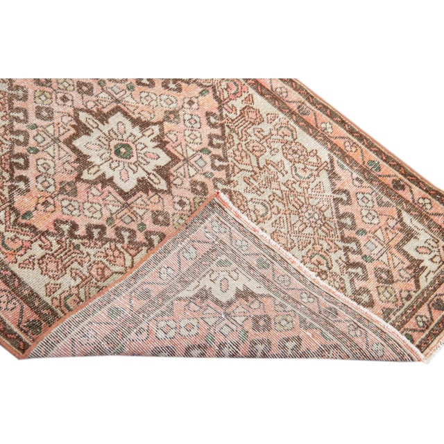 Beautiful vintage Persian distressed hand-knotted wool rug with a peach color field. This piece has brown and beige...