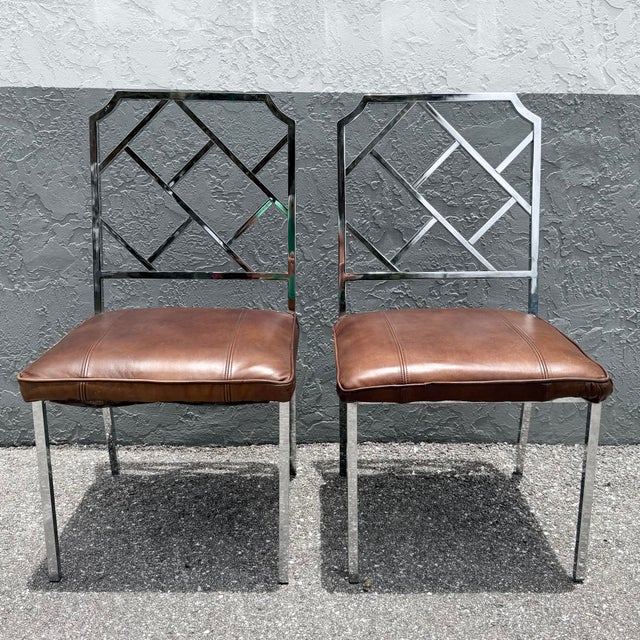 A striking pair of Mid Century Modern dining chairs featuring polished chrome frames with an elegant Chippendale-inspired...