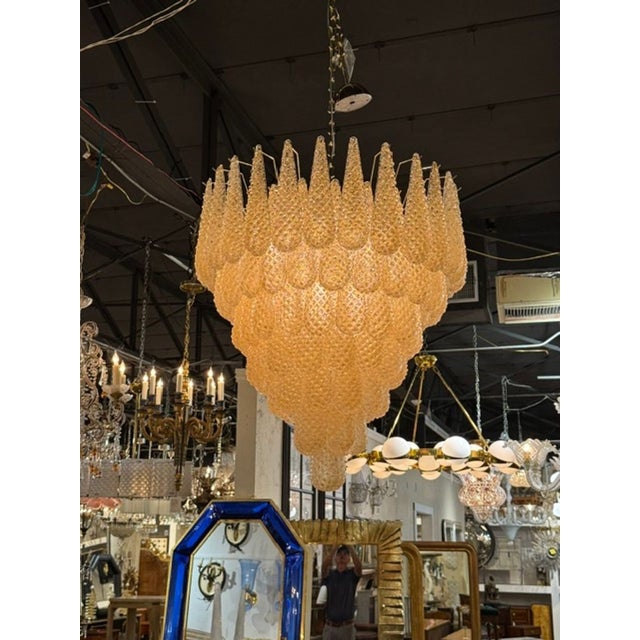 The Murano Gold Granola Glass Tear Drop Chandelier is a stunning and elegant lighting fixture. The chandelier features a...