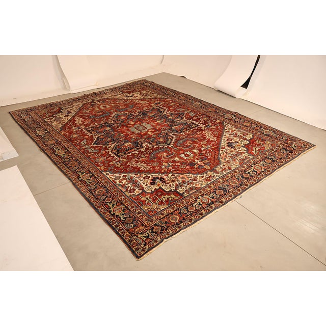 High Quality Antique Hand Knotted Persian Heriz Room Size Rug Featuring A Bold Geometric Central Medallion Set Within A...