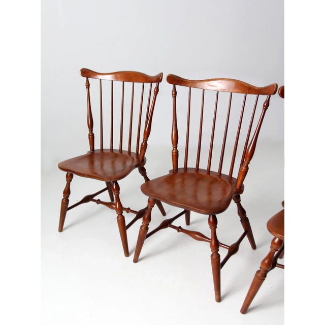 A classic set of four Windsor dining chairs dating to the 1950s, featuring the timeless fan-back design with slender...