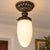 Art Deco-style milk glass flush mount ceiling light with a swirling white glass globe and ornate vintage metal fixture....