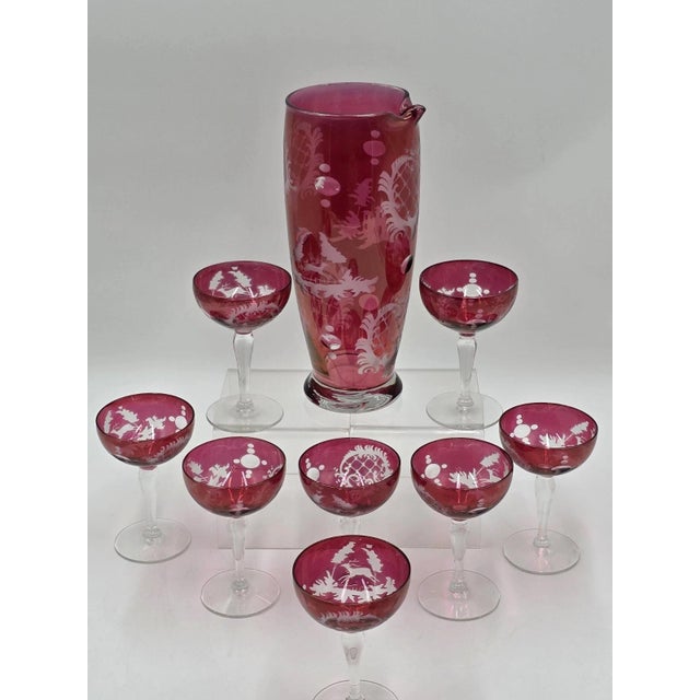 This rare set of 8 antique Edwardian wine cranberry glass engraved etched wine glasses and pitcher is a stunning piece of...