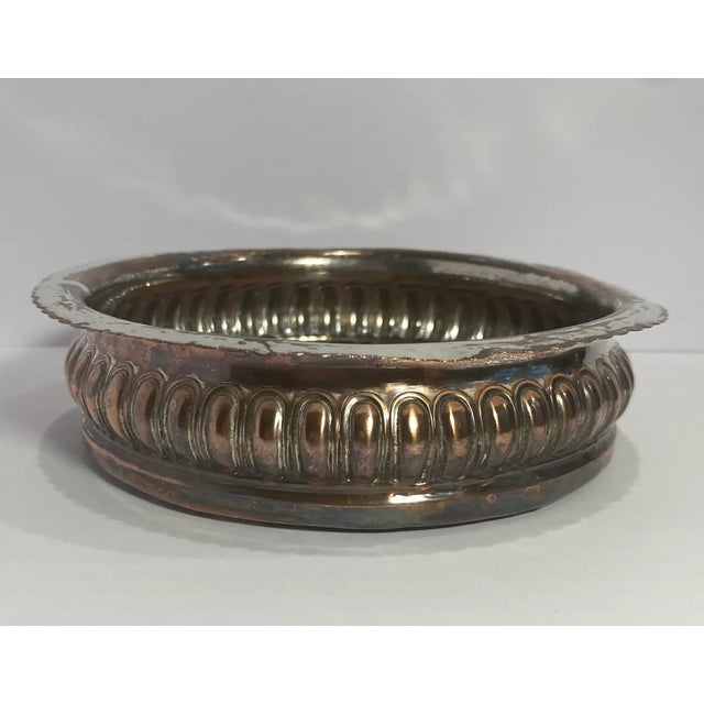 Antique silverplate on copper wine coaster. The body is gadrooned projecting a scalloped rim, wooden bottomed with a...