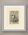 Two little girls are absorbed in drawing in a room hung with framed pictures. The older girl, her long dark hair falling...