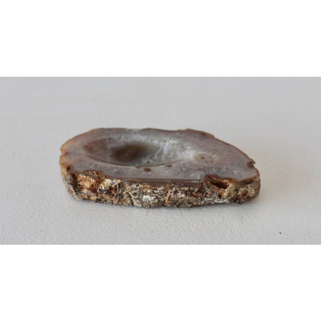 A polished brown and white agate geode slice featuring a central quartz crystal scallop cave. Exhibiting banding patterns...