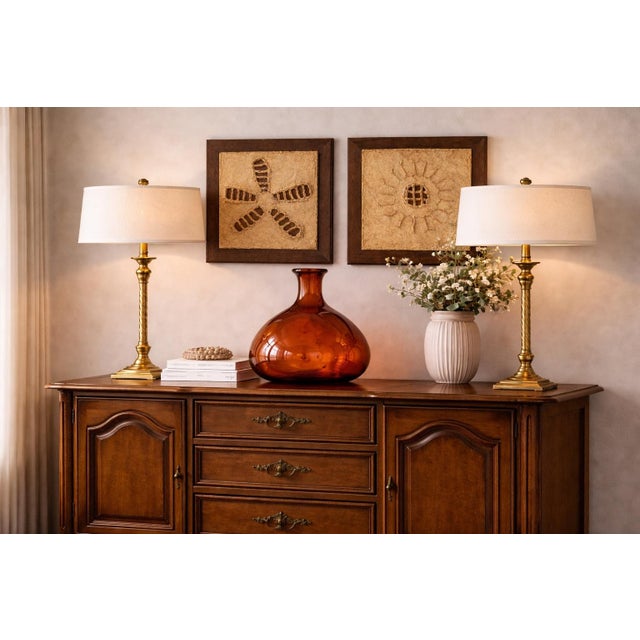 A striking pair of sculptural buffet table lamps, newly refinished in a warm sunlit brass tone and topped with tailored...