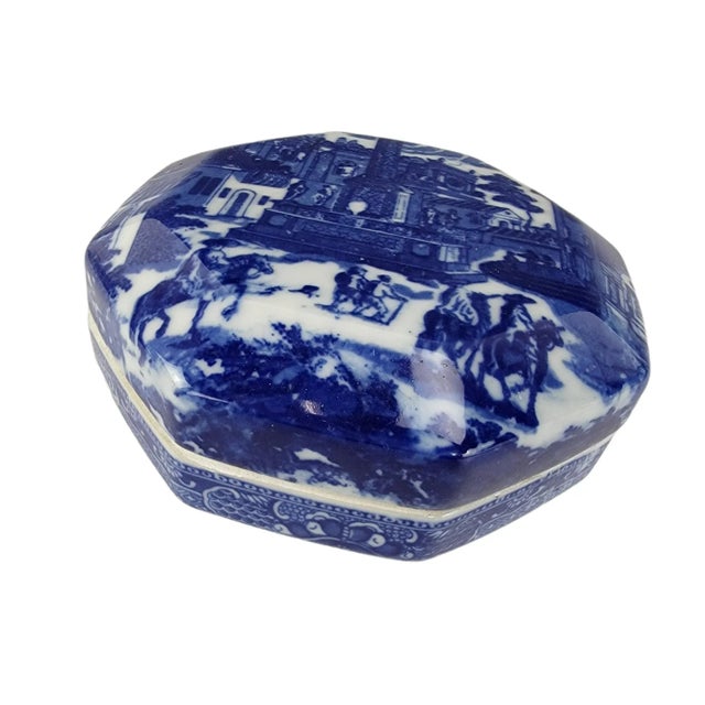 A porcelain trinket box painted in flowing cobalt and white, its glaze creating soft transitions of color that recall the...