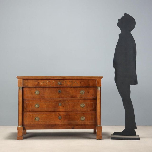 Empire walnut chest of drawers from the early 19th century, featuring an imposing structure and later brass veneer...