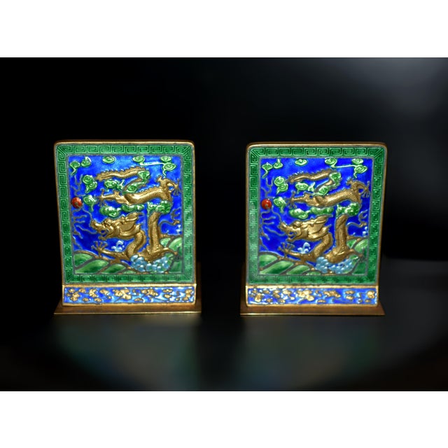 From a private collection, a spectacular pair of solid brass enameled bookends. Each features a gilded dragon emerging...