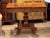 A Regency sofa table in figured wood with crossbanded edges and drop leaves that extend the top. The frieze contains three...