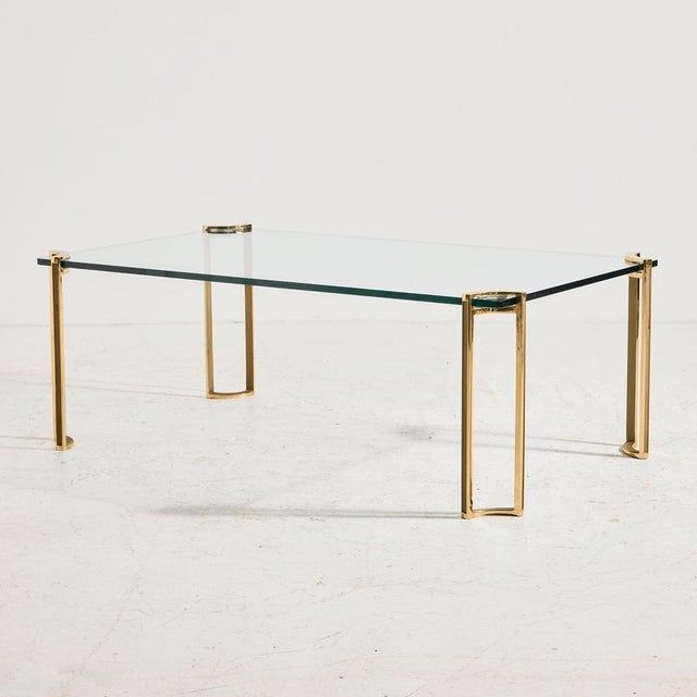 A classic-style coffee table with brass legs and a tempered glass top from 1970s France. with some surface scratches and...