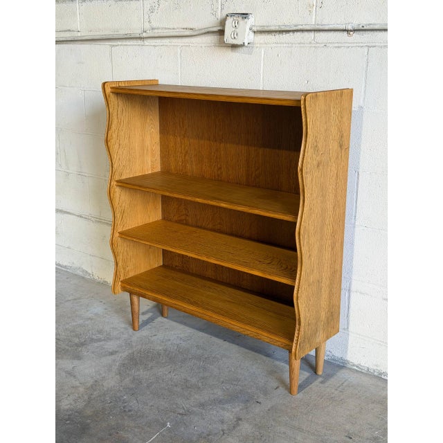 This vertical storage unit features open shelving and sculpted wave-like side profiles. Its functional design and clean...