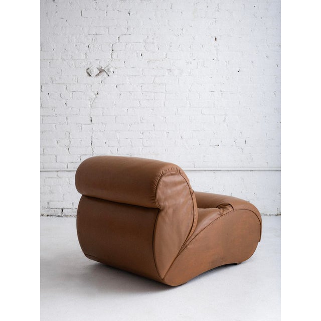 Italian mid-century lounge chair in cognac leather upholstery. This piece features a space-age silhouette and wide tufts...