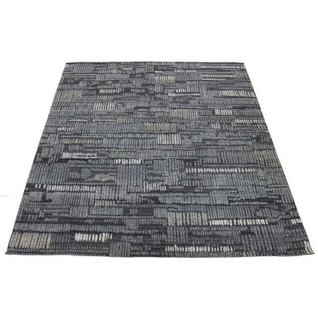 This hand-knotted wool rug has a luxurious charcoal-gray base with a geometric pattern in light gray and beige inspired by...
