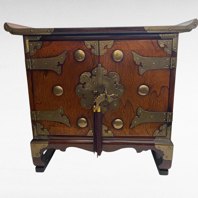 Vintage East Asian two-door accent cabinet in warm toned wood, dating to the 1960s–70s, in the tansu/bandaji tradition....