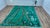 A saturated emerald-green Beni Mrirt, crossed by camel-tan and black abstract branching linework — part lightning bolt,...