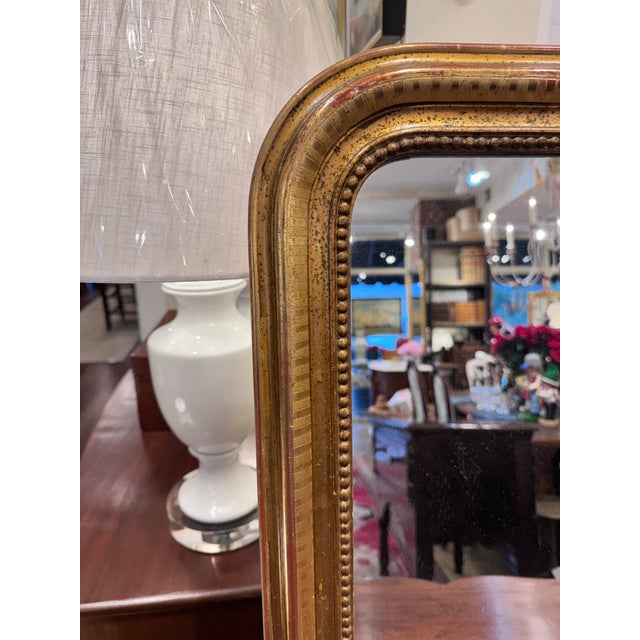 This is an antique French 19th-century Louis Philippe giltwood mirror with a gold leaf frame. The frame features the...
