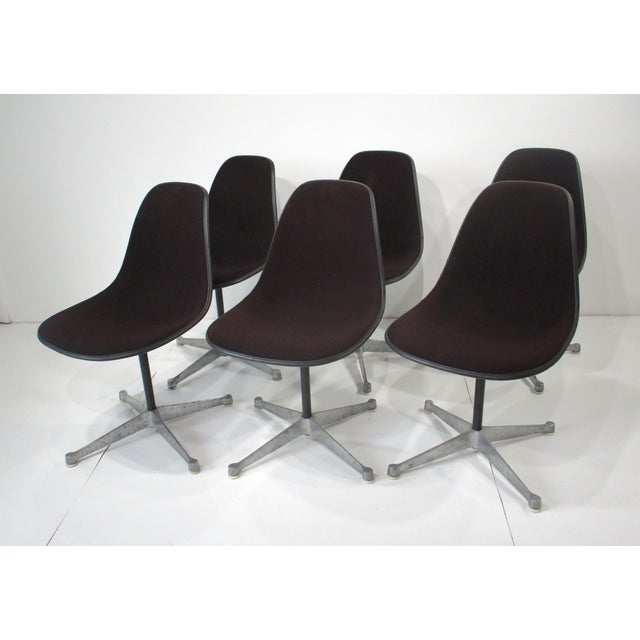 A set of six swiveling Eames Aluminum Group dining chairs with cast four star bases having plastic foot pads to protect...
