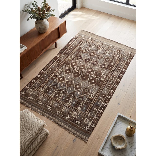 This large handwoven Afghan Ghalmori Maimana kilim has a deep brown and charcoal gray base with muted blue, cream, taupe,...