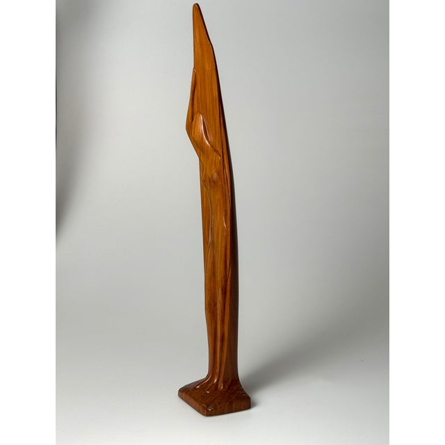 Hand-carved sculpture in solid teak depicting a stylized female figure leaning into a boat. One hand supports the boat...