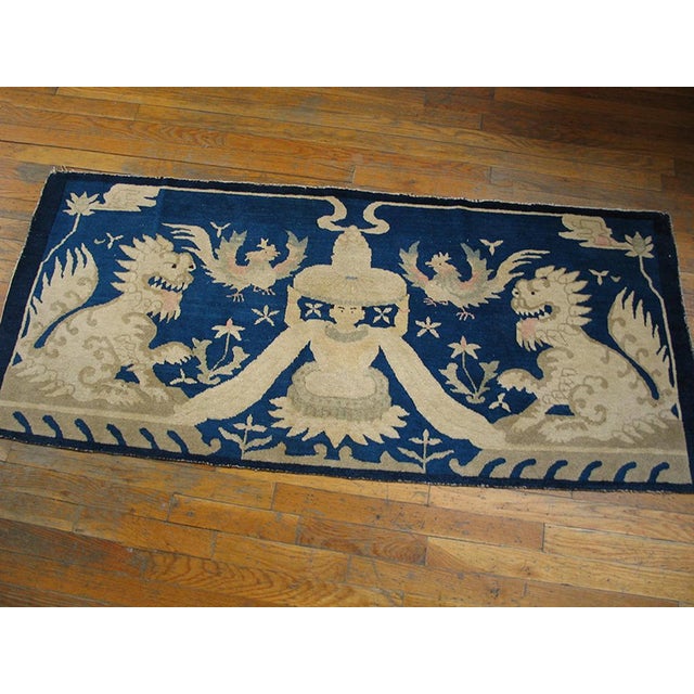 This extraordinary borderless rug displays two facing, seated fierce lion-dogs guarding a central human statue figure...