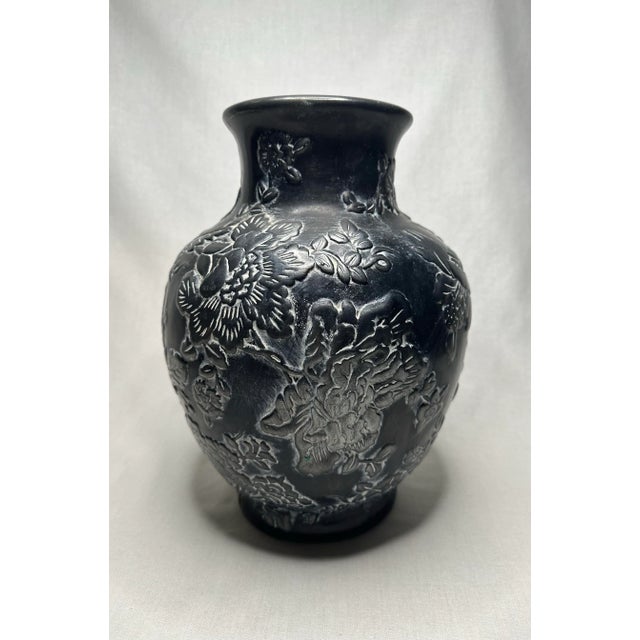 The floral motif is enhanced in a white-washed patina on a dark background on this substantial size vase. The bulbous...