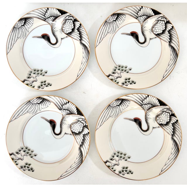 A striking set of four Fitz & Floyd fine porcelain dinner plates in the elegant “Crane With Pine” pattern, produced in...