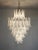 Handblown glass chandelier, composed of 85 curved, clear glass pieces, which are arranged on 7 tiers, suspended from a...