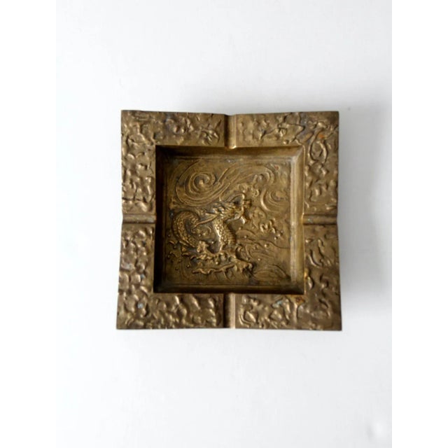 This is a vintage heavy brass ashtray. The square catchall tray features a sea dragon motif with raised relief design.
