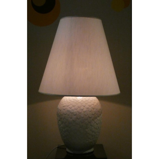 Original table lamp designed by Tommaso Barbi and crafted from a single piece of white glazed ceramic in the shape of a...