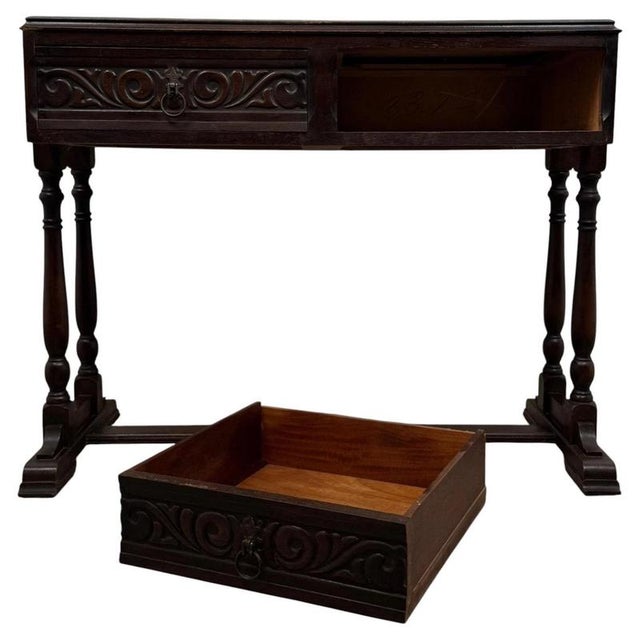 A handsome and beautifully crafted 20th-century oak side table, distinguished by its intricately carved drawer fronts,...