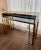 A nice sized Modern brass console table with “floating “darker plate glass top in the perfect size. This glasses top table...