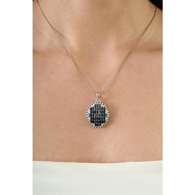 A striking Art Deco-inspired statement pendant, this piece features a precisely arranged mosaic of baguette-cut blue...