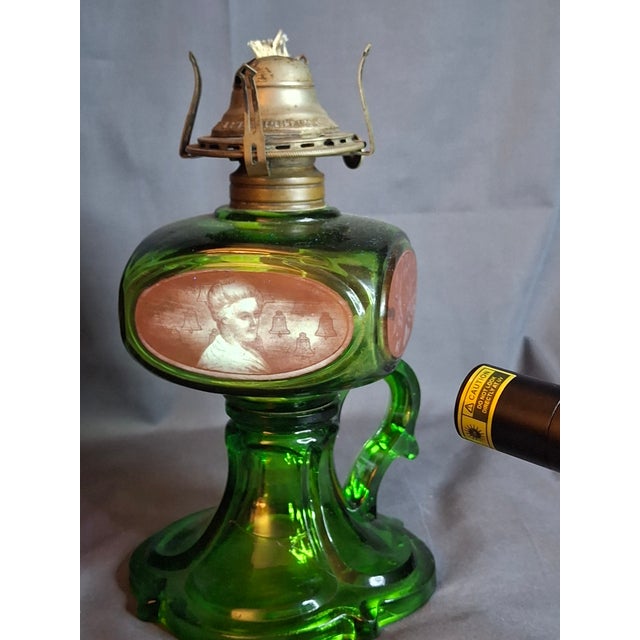 Offering a rare and visually striking antique emerald green glass kerosene finger lamp. This piece features a unique...