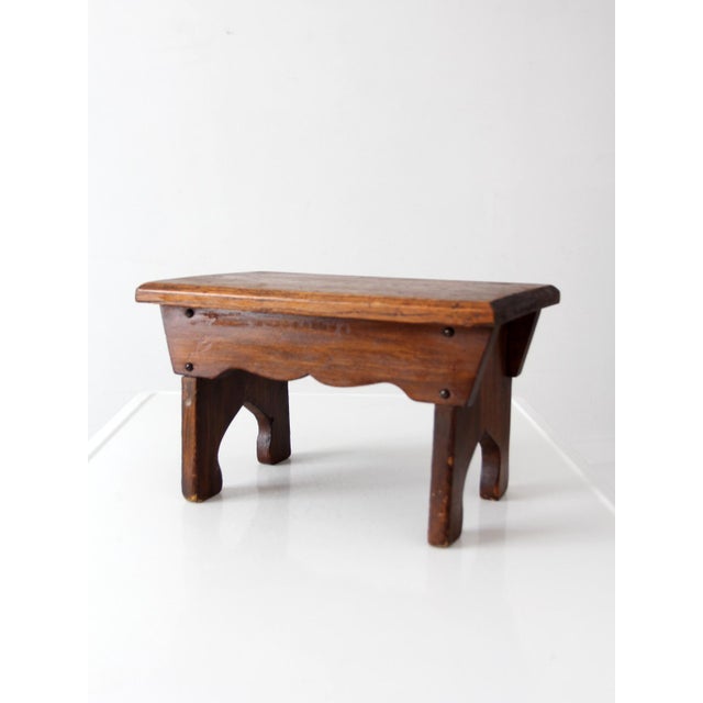 This early 20th century wooden farmhouse stool features a solid oak top, scalloped apron, and cutout legs with a...