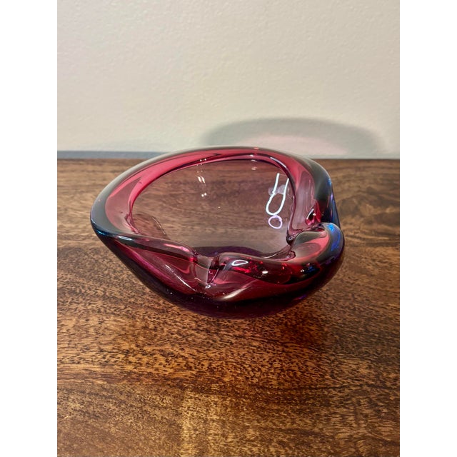 A sculptural 1960s blown studio glass bowl in the Murano attributed, featuring vibrant raspberry tones suspended in clear...
