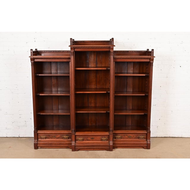 A gorgeous antique Eastlake Victorian triple bookcase In the manner of Herter Brothers USA, Circa 1880s Carved walnut,...